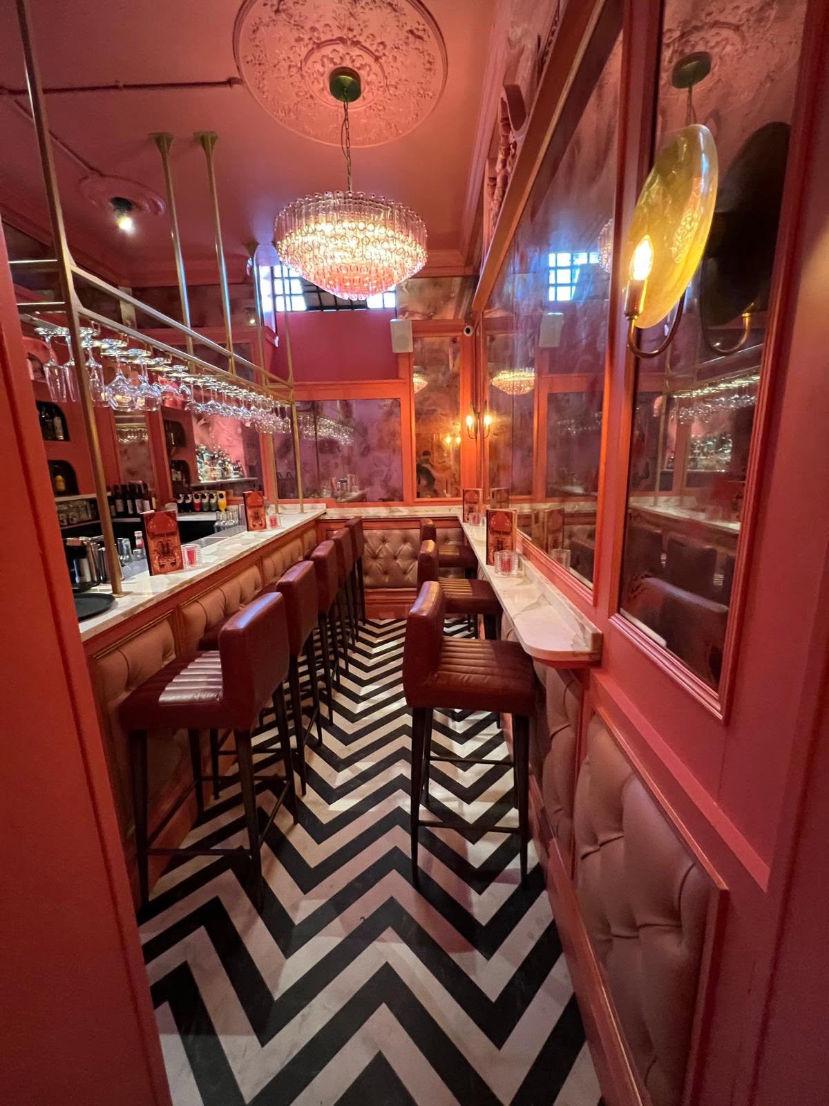 Narrow bar run with brass overhead glass rack, marble counter and ornate ceiling rose