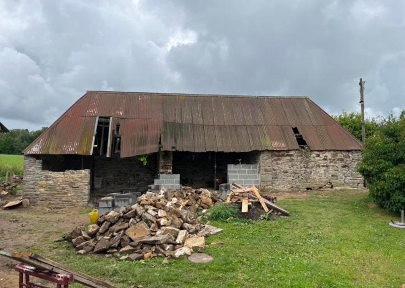 Before: long stone barn with rusted corrugated roof and open cart entrances