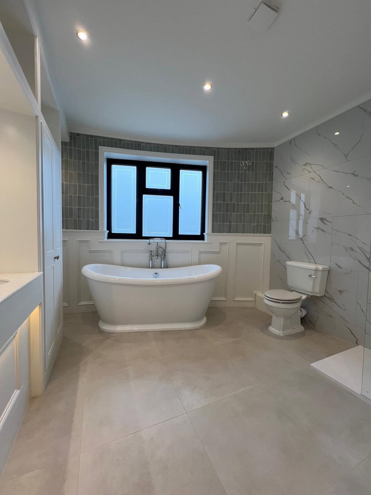 Bathroom with freestanding bath and vertical grey tiling