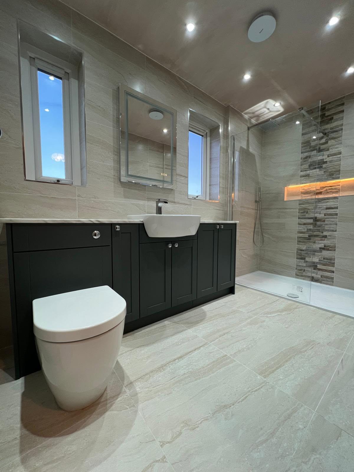 Wet room with full height stone effect porcelain tiling, dark green shaker fitted furniture and walk in shower