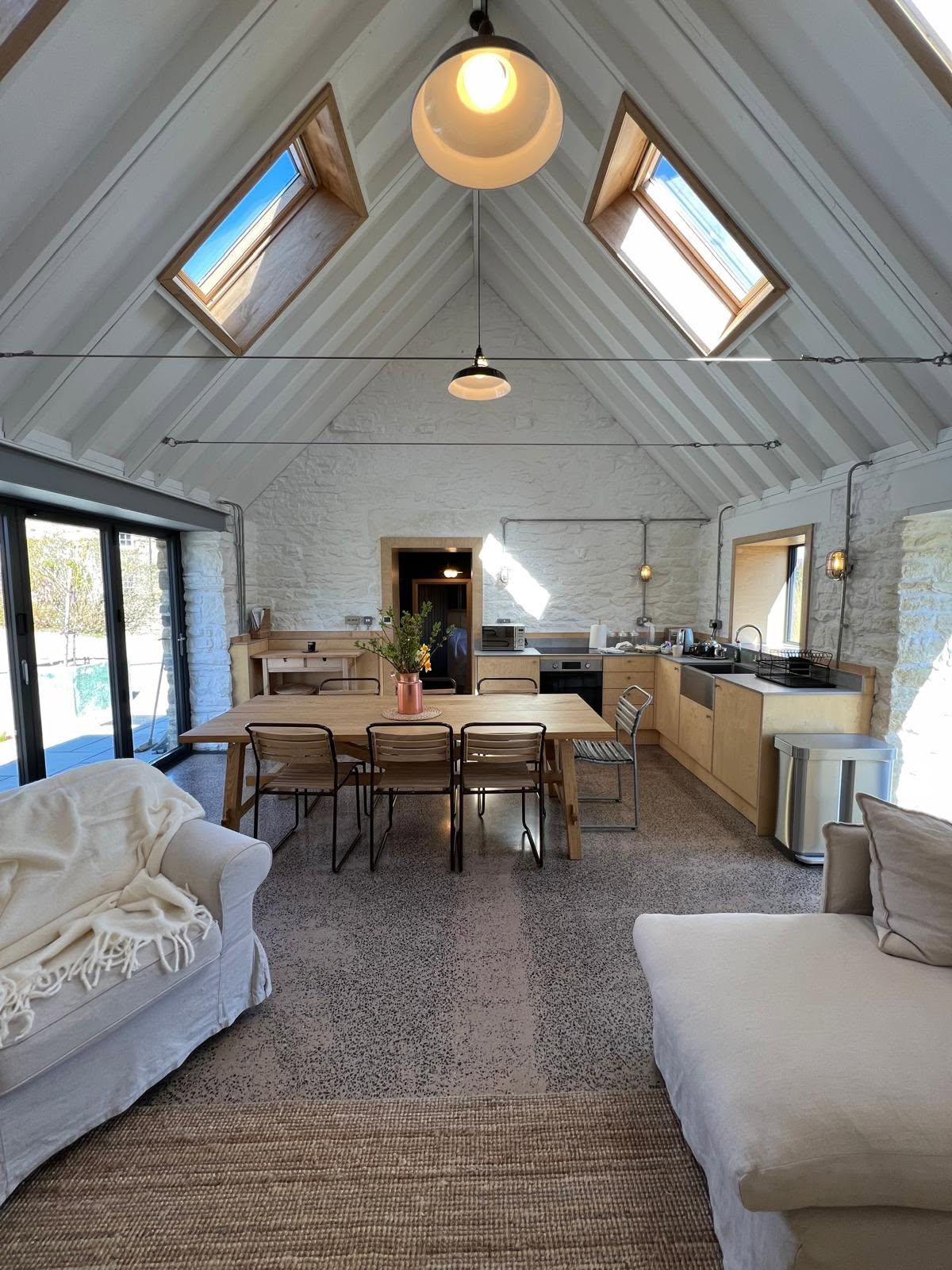 Finished open plan living with vaulted white lined roof, oak rooflights, limewashed stone, ply kitchen and terrazzo floor