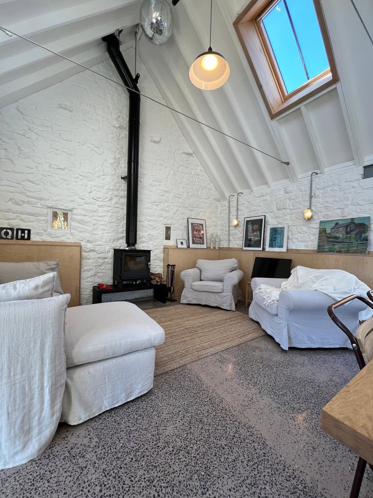 Lounge from the dining table with high vault, stove flue, artwork on the ply ledge and terrazzo floor