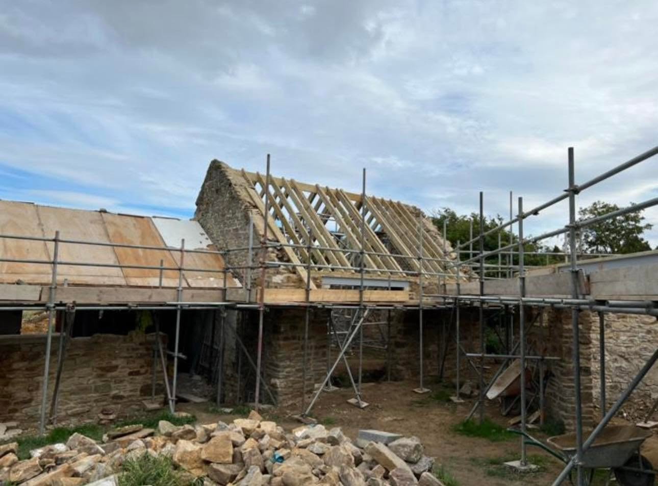 Progress: scaffolded gable with new timber roof structure going on over retained stone walls