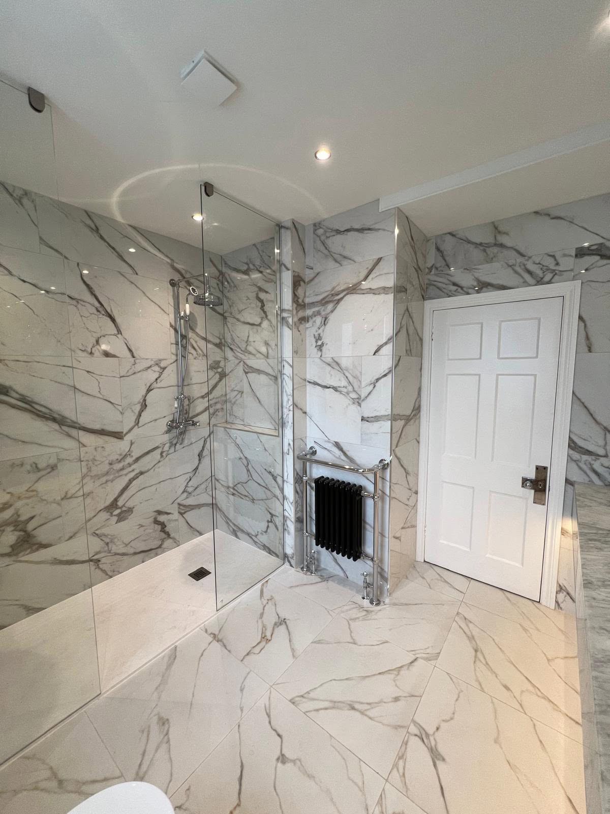 Marble tiled shower area with black column radiator