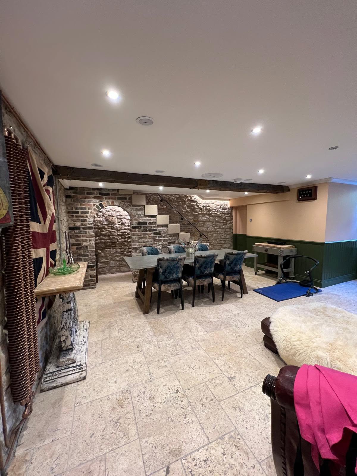 Opposite long view with Union flag on exposed stone, copper radiator, dining zone and gym corner
