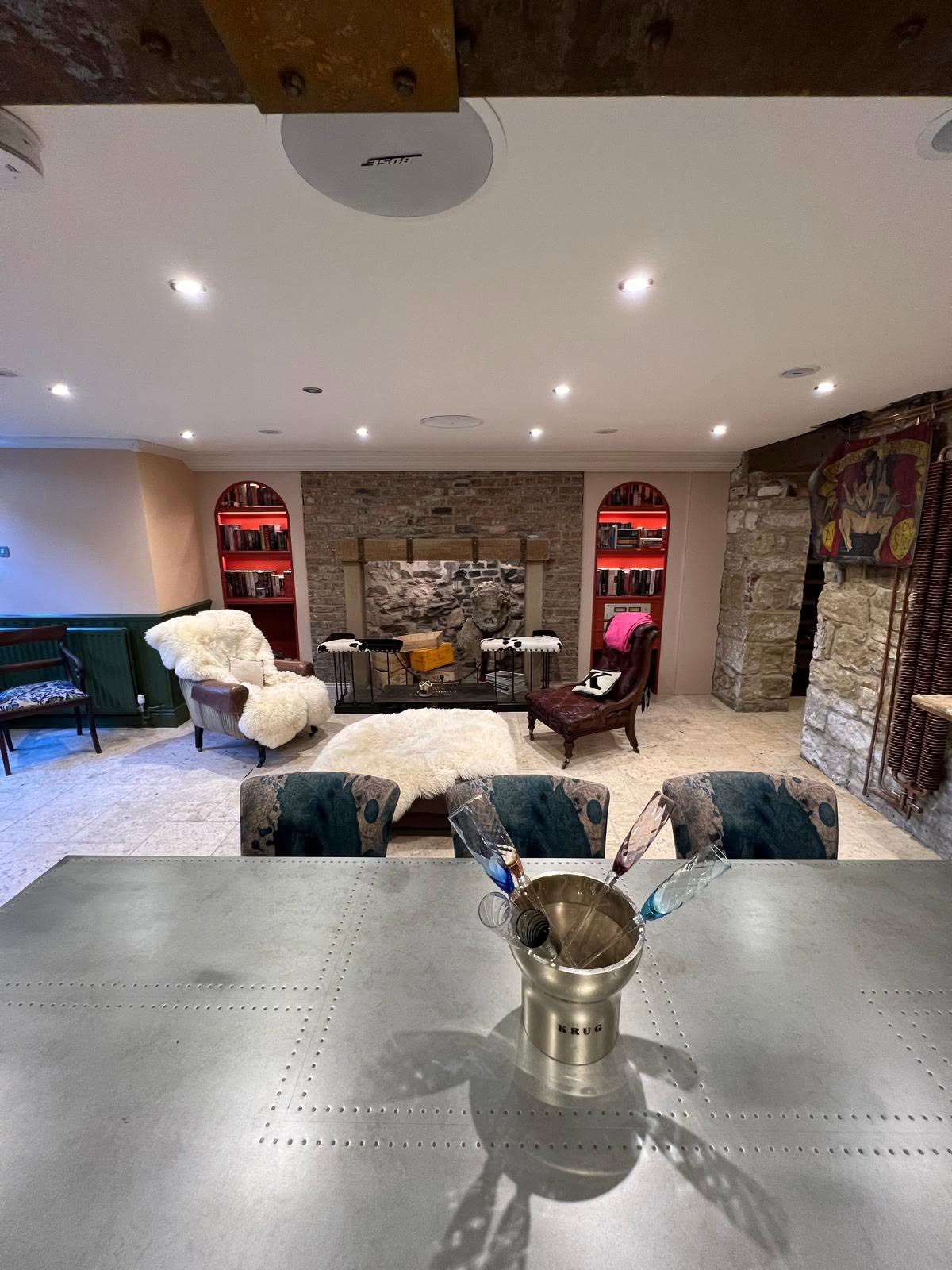 Basement lounge from zinc-topped dining table with exposed steel and timber beam and red-lacquered arched book niches