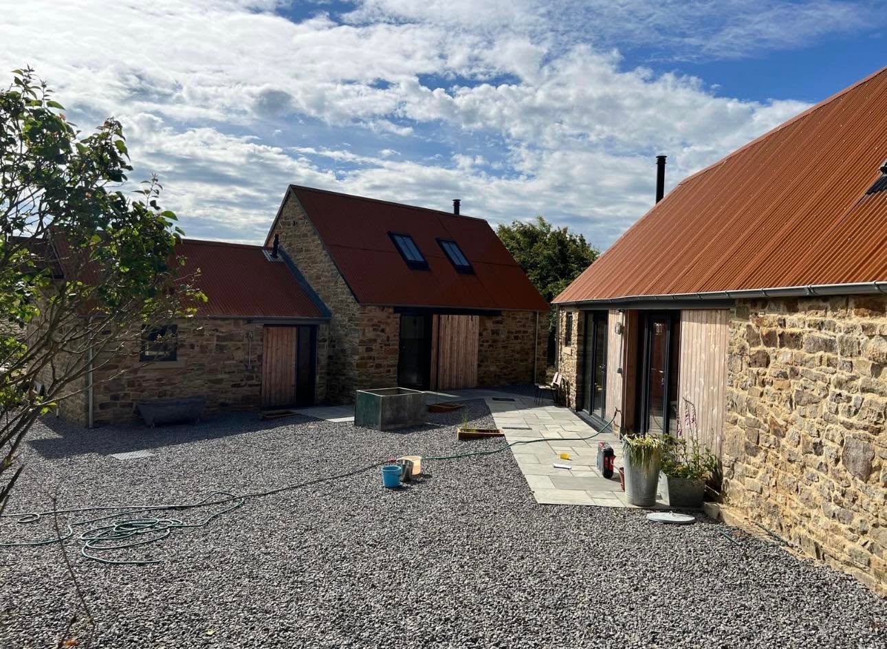 Courtyard between the converted barns with stone paving, gravel yard, larch cladding and bi-fold doors