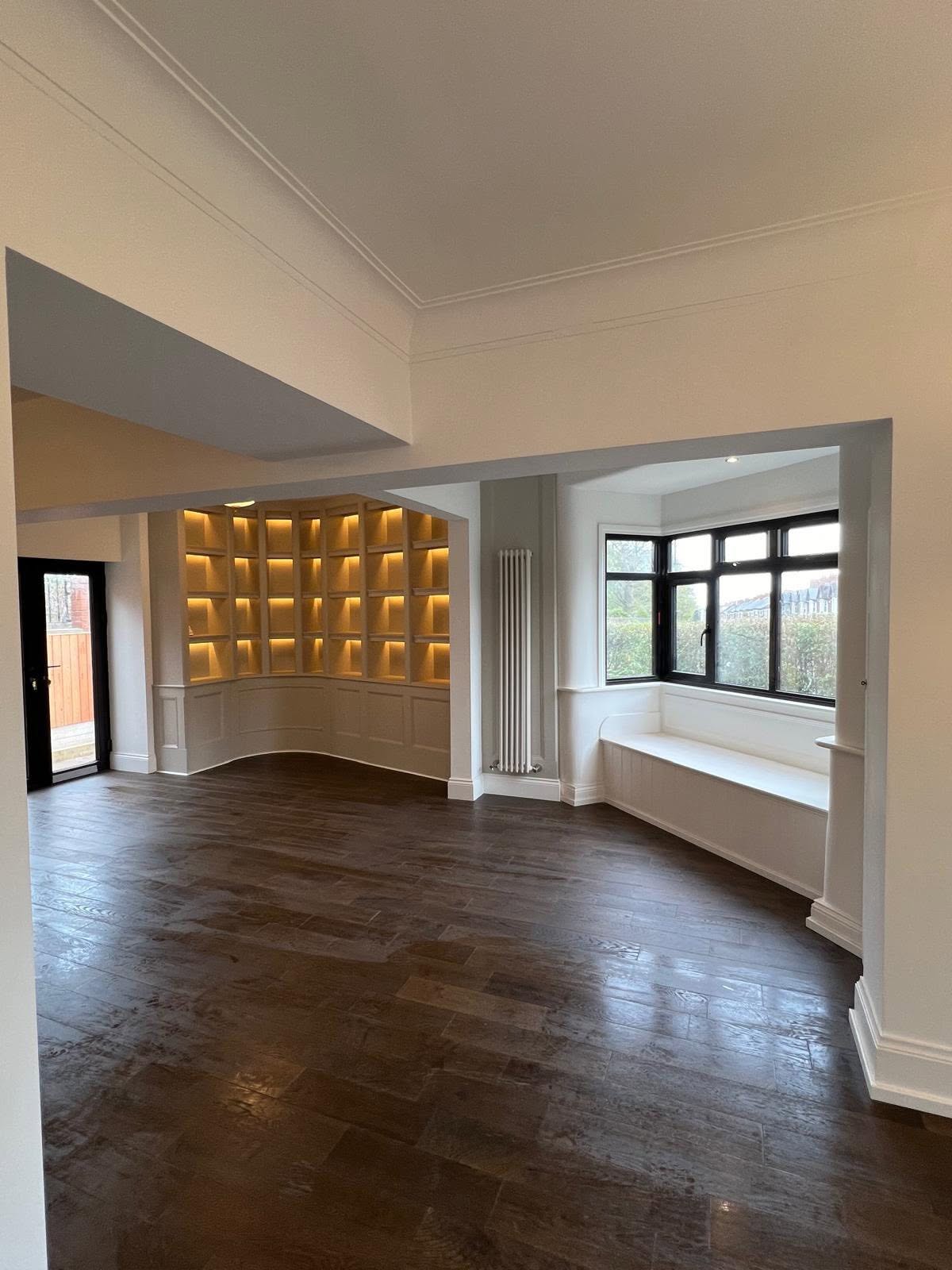 Living room with a large curved backlit bookshelf built by Kay Homes