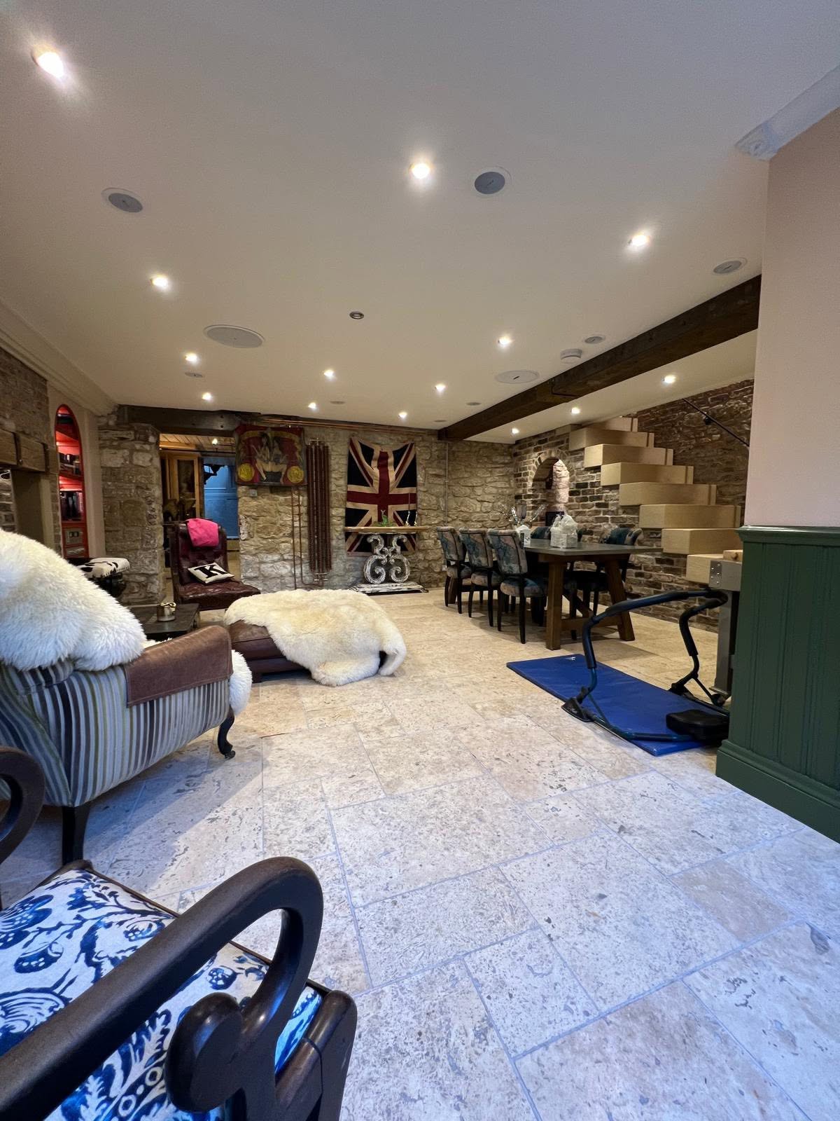 Full length basement view toward the stone stair with exposed stone and brick walls and travertine floor