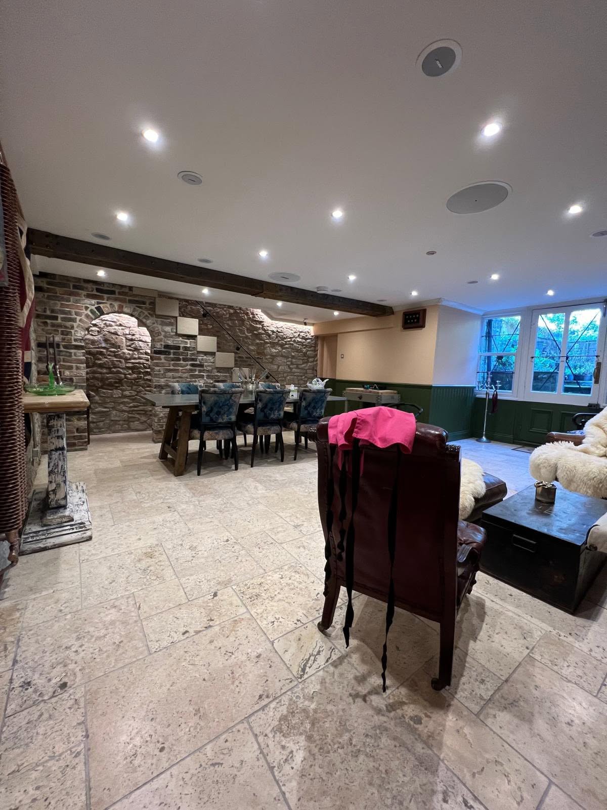 Basement long view with stone arch doorway, understair stone steps, dining zone and green panelled walls