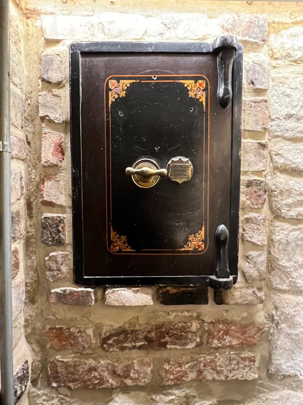 Retained Victorian cast iron wall safe with gilt lining set into the exposed stone wall