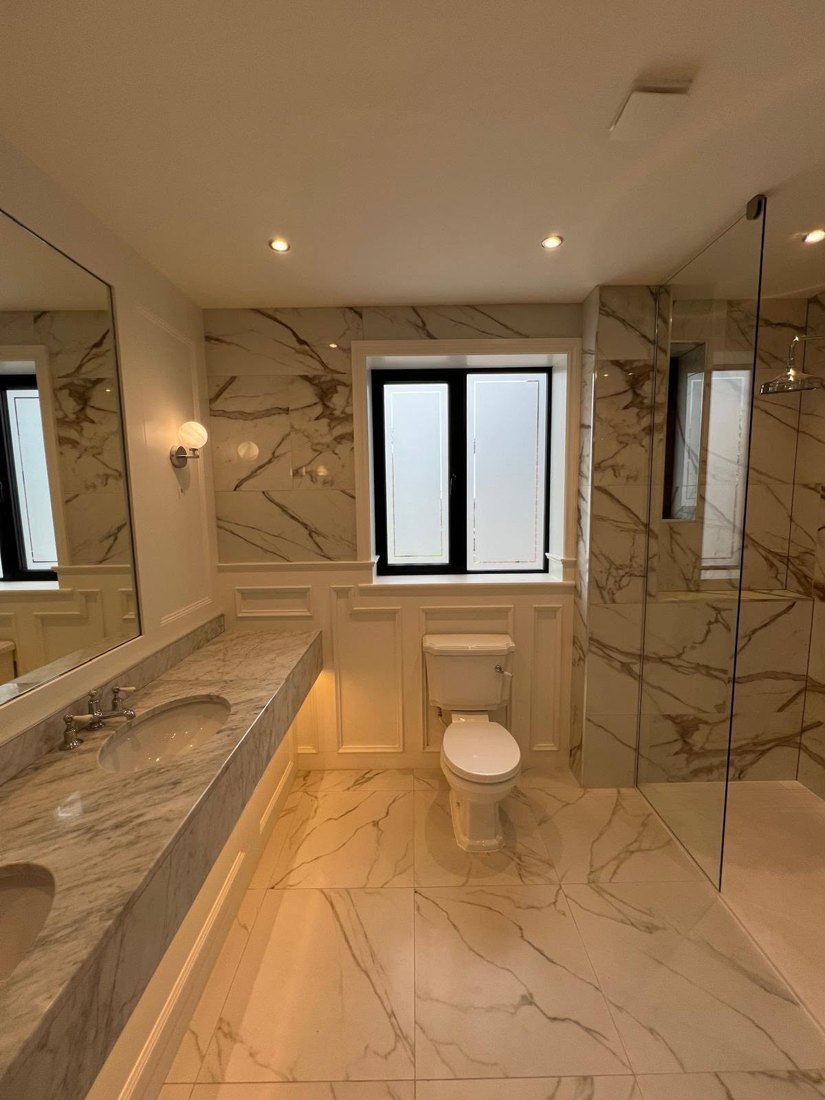 Marble effect bathroom with floating vanity, under-vanity accent lighting and white ceramic toilet