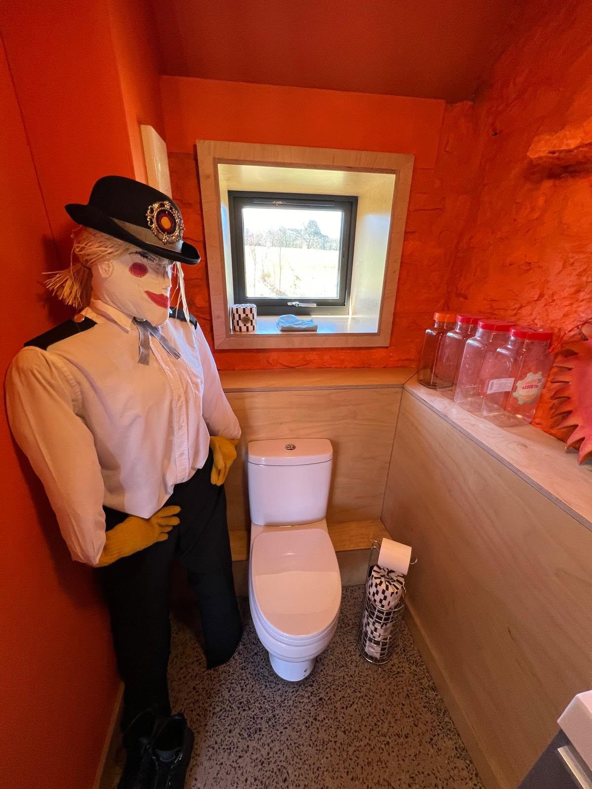 Cloakroom with bold orange walls against ply panelling and a ply lined window reveal