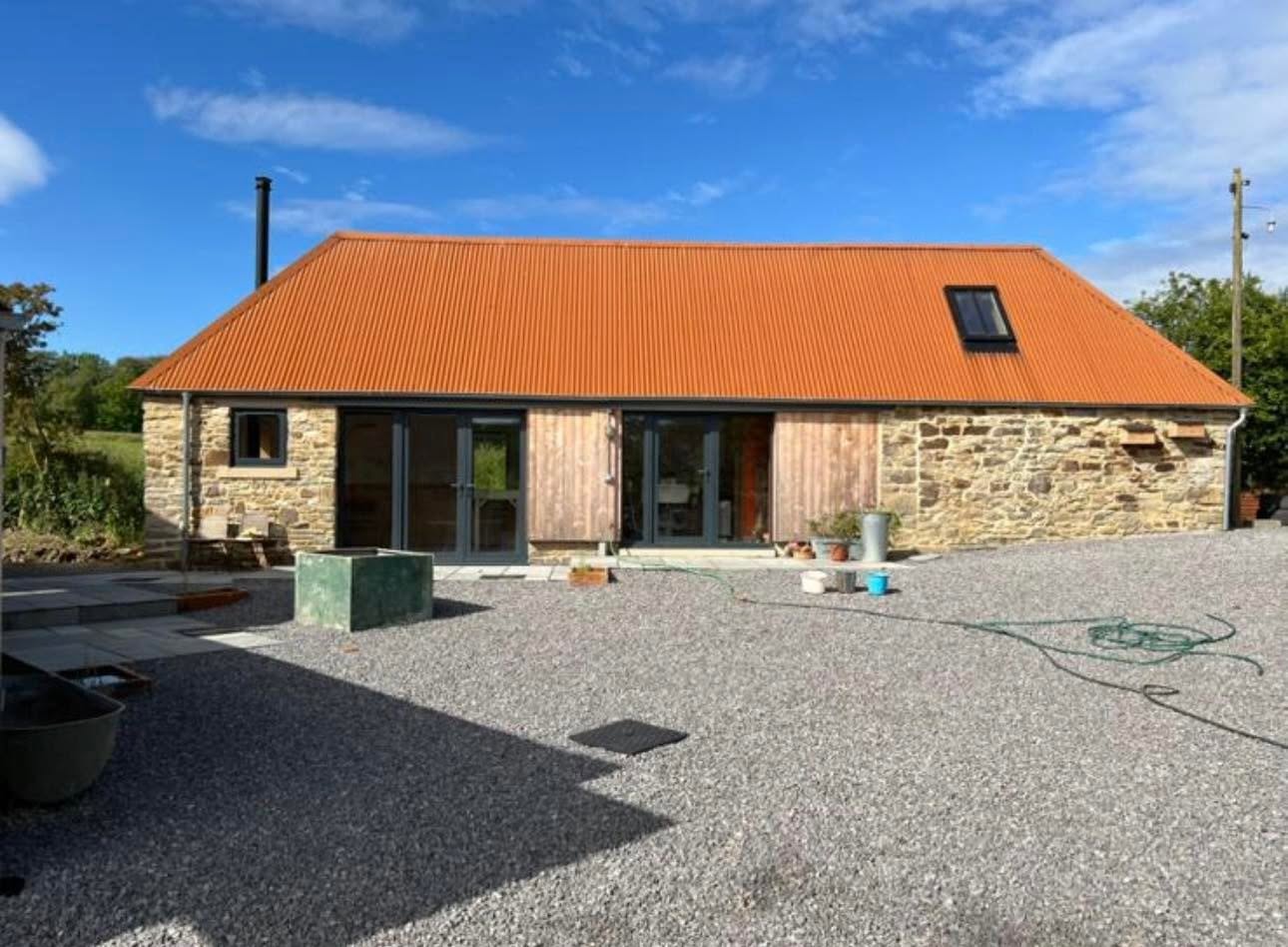 Completed long elevation with French doors, vertical larch cladding infill panels and stone walls
