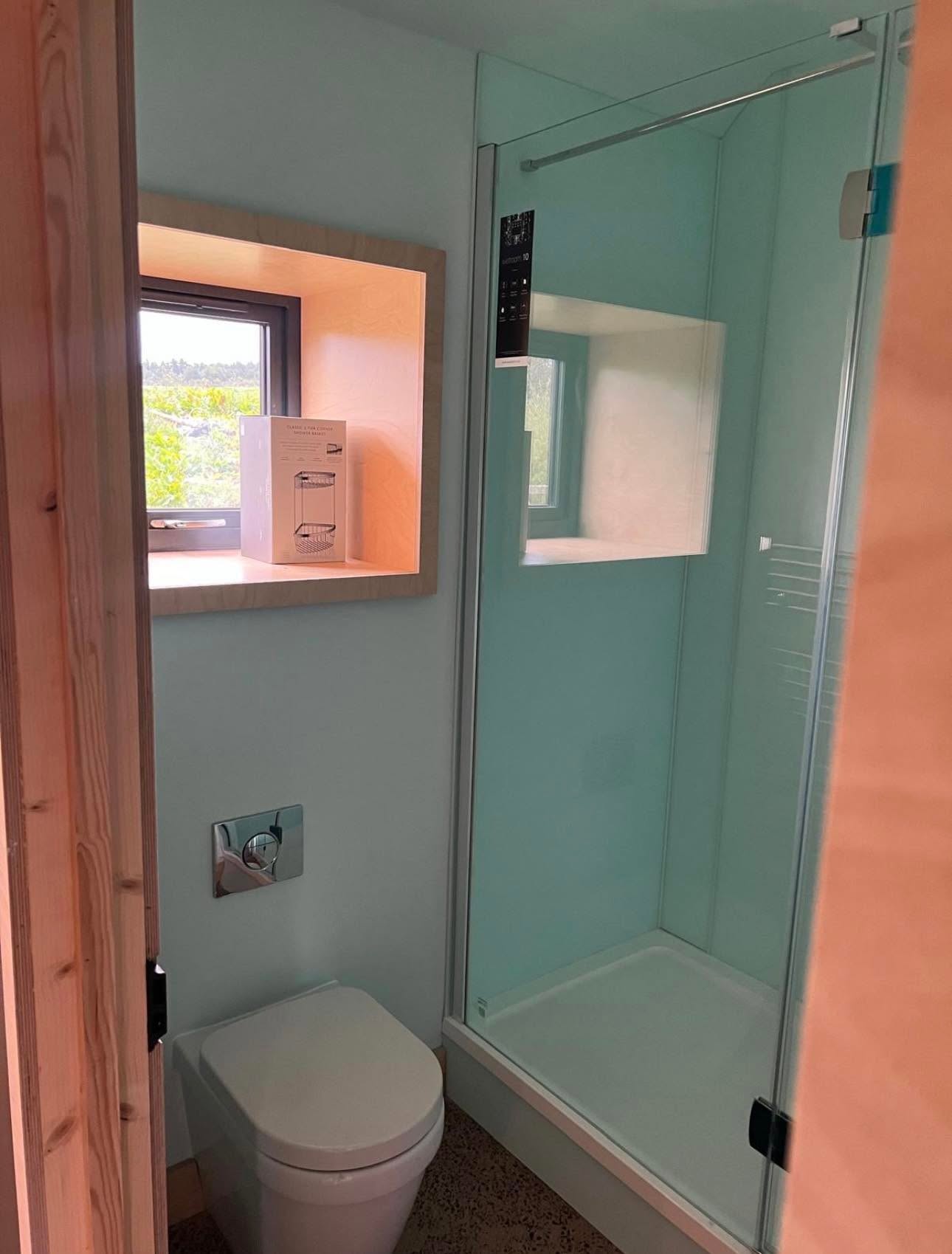 Shower room with full height glazed shower with rain head, wall hung WC and terrazzo floor