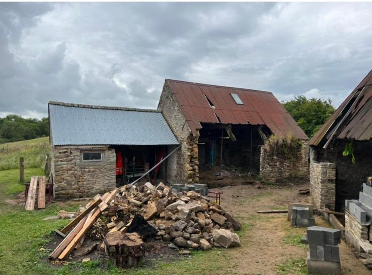 Before: derelict stone barns with failing corrugated roofs and salvaged stone stacked in the yard