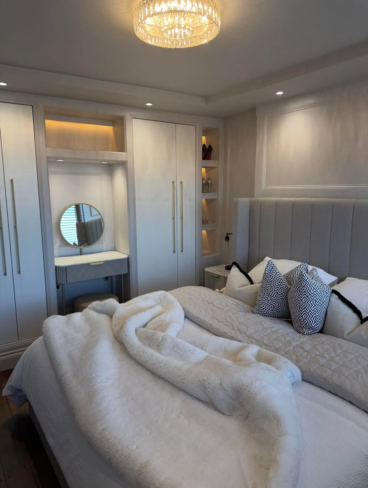 Dressing nook close view with lit niches, shelving, round brass mirror, fluted dressing table and crystal flush light