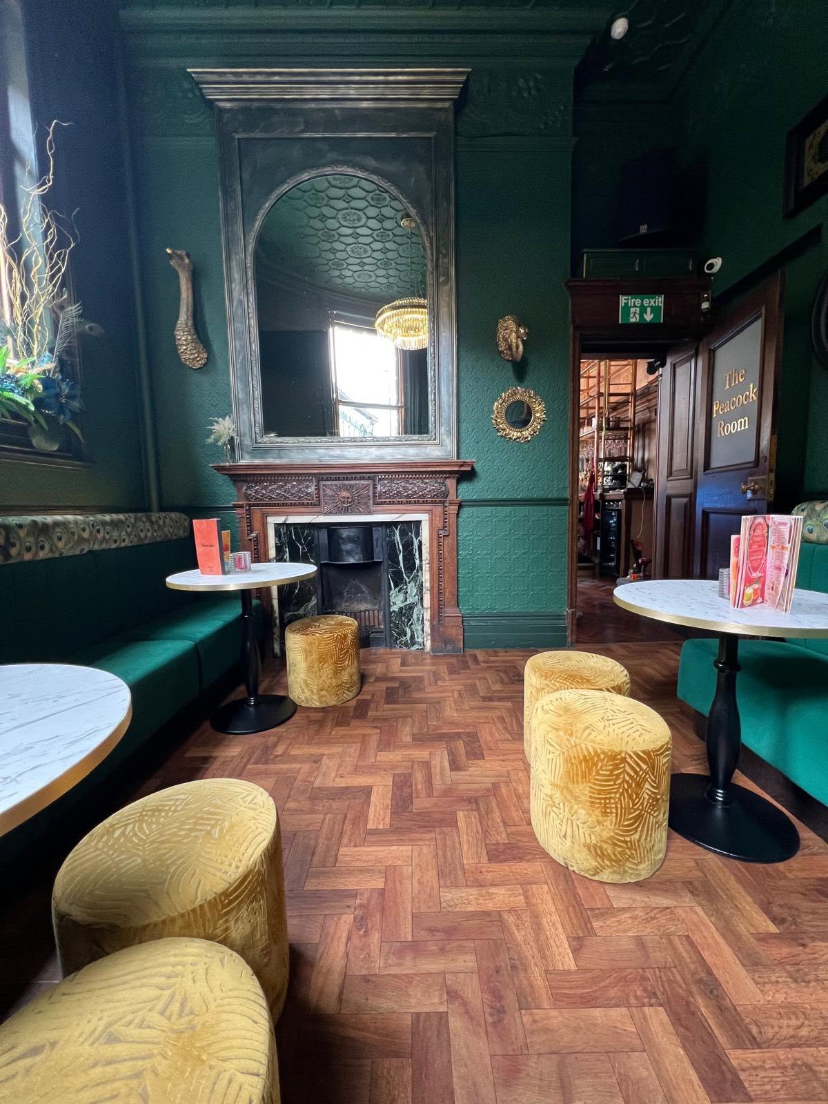 The Peacock Room with dark green embossed walls, carved timber fireplace and herringbone parquet