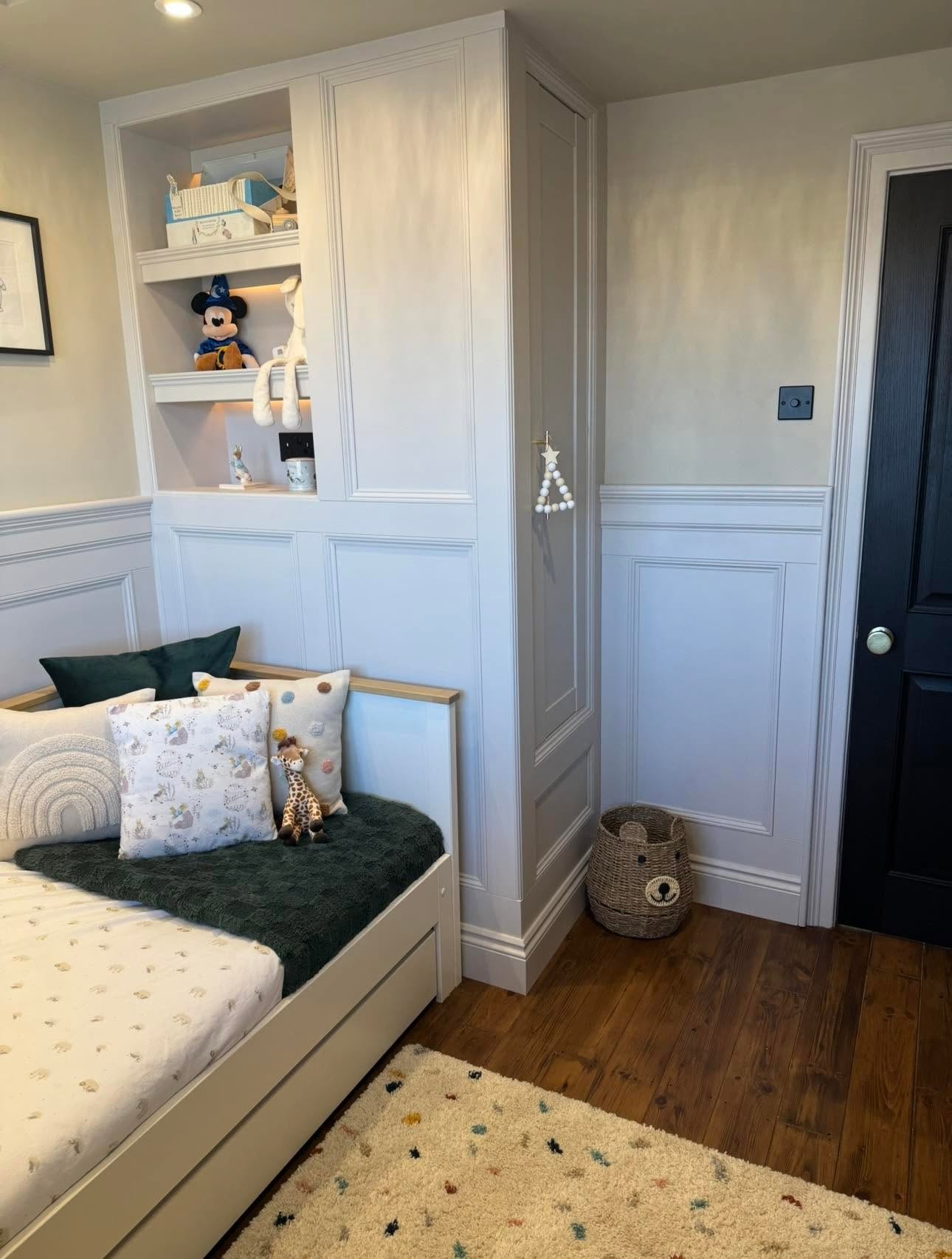 Child's bedroom fitted joinery with full height panelled wardrobe, lit shelf niche and dado panelling to black door