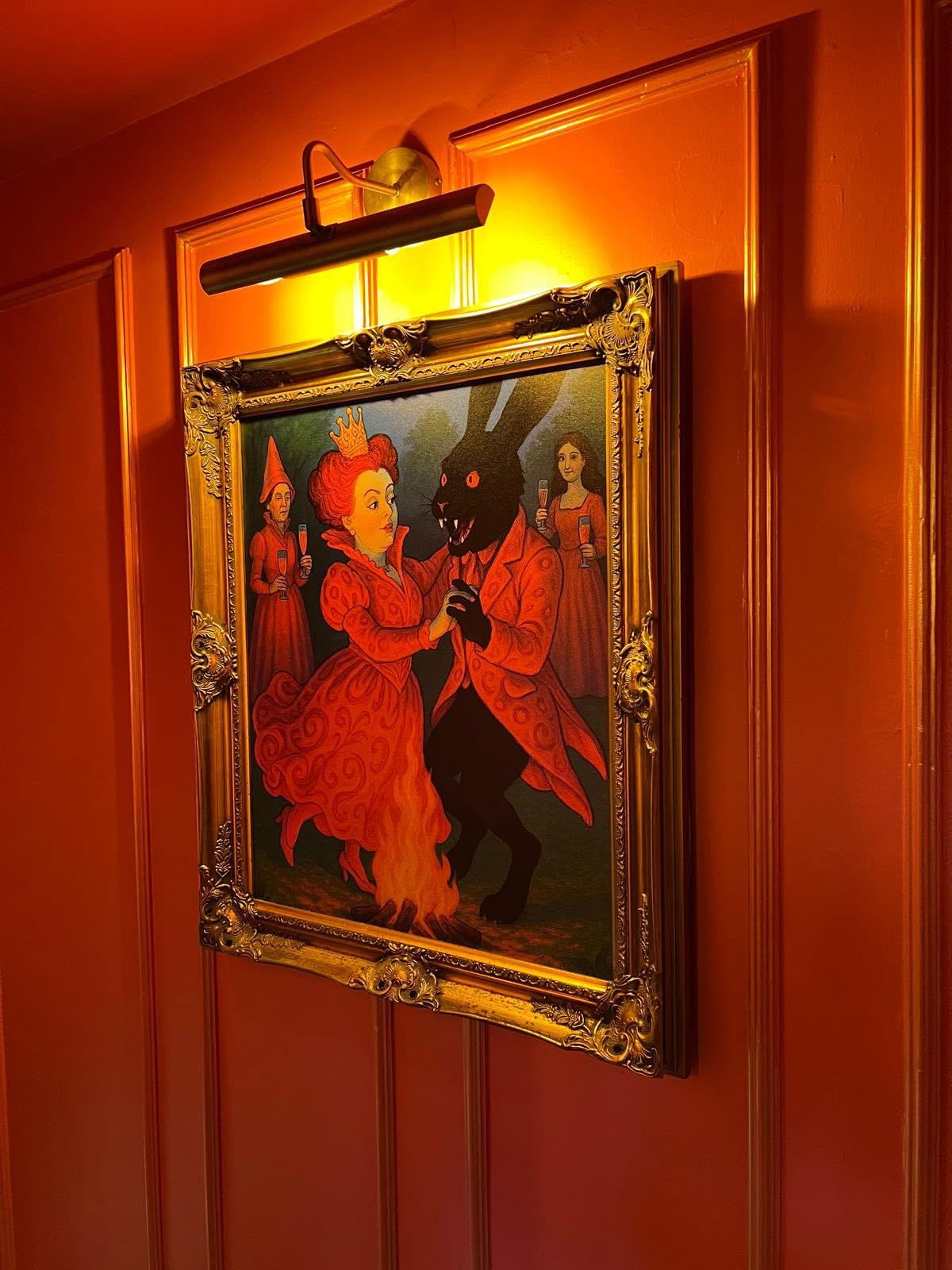 Gilt-framed artwork with brass picture light on coral panelled joinery