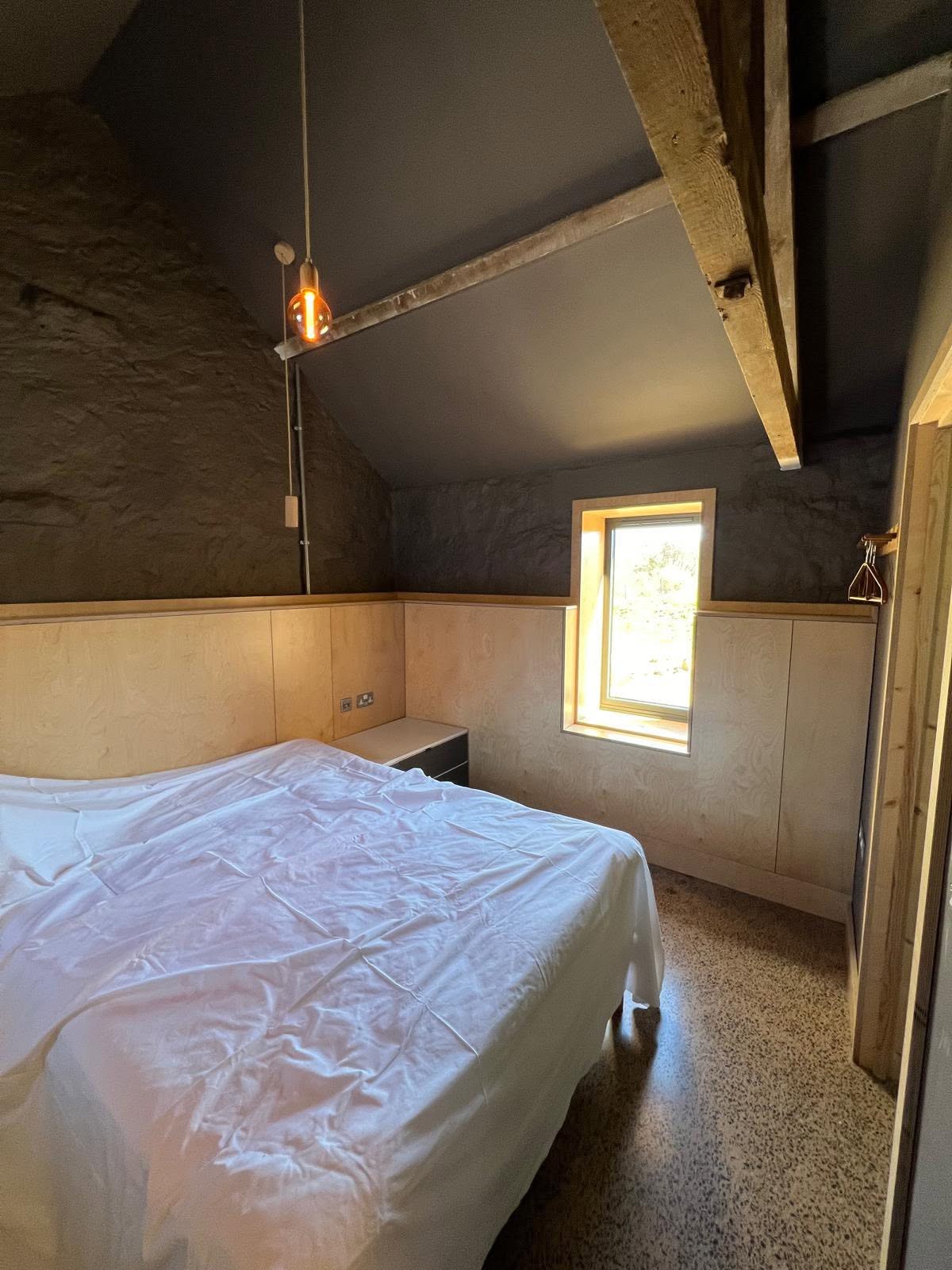 Bedroom with charcoal walls over birch ply panelling and fitted wardrobes, retained timber tie beam