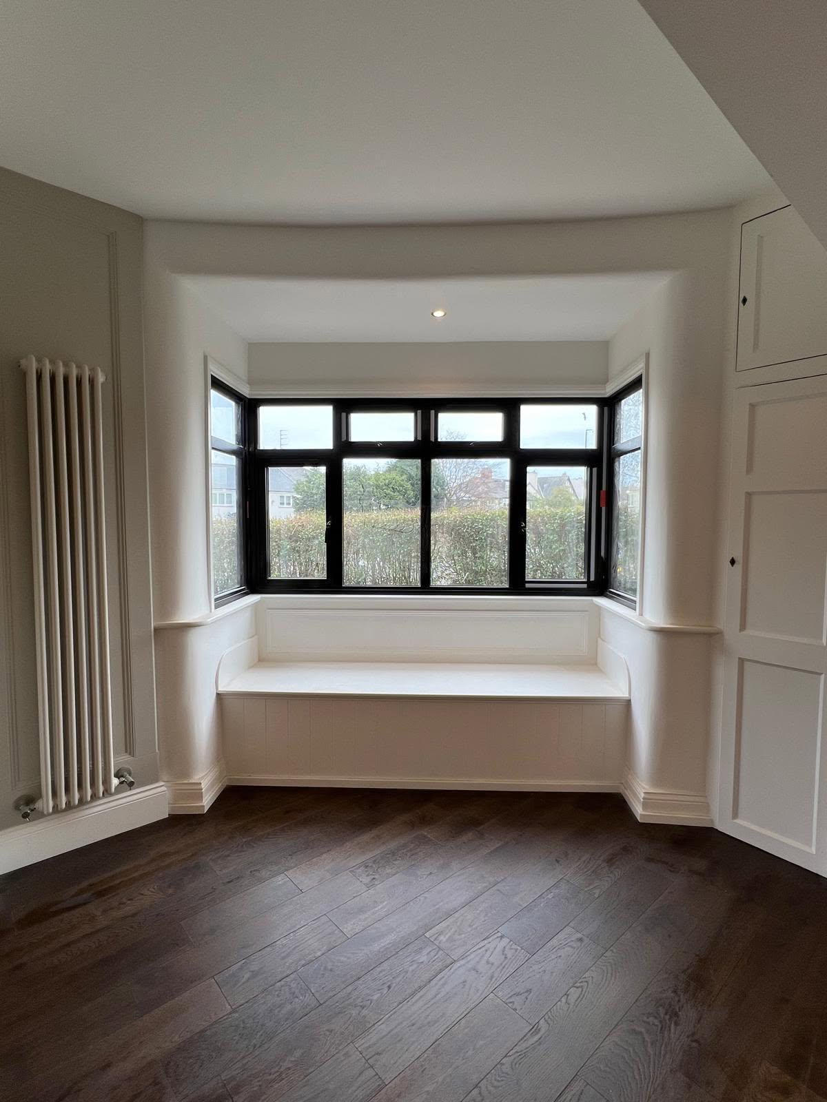 Built in window seat under a bay window with dark timber flooring