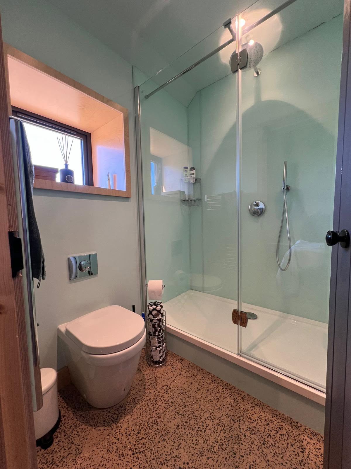 Shower room with frameless glass walk in shower, rain head, wall hung WC and ply lined window box