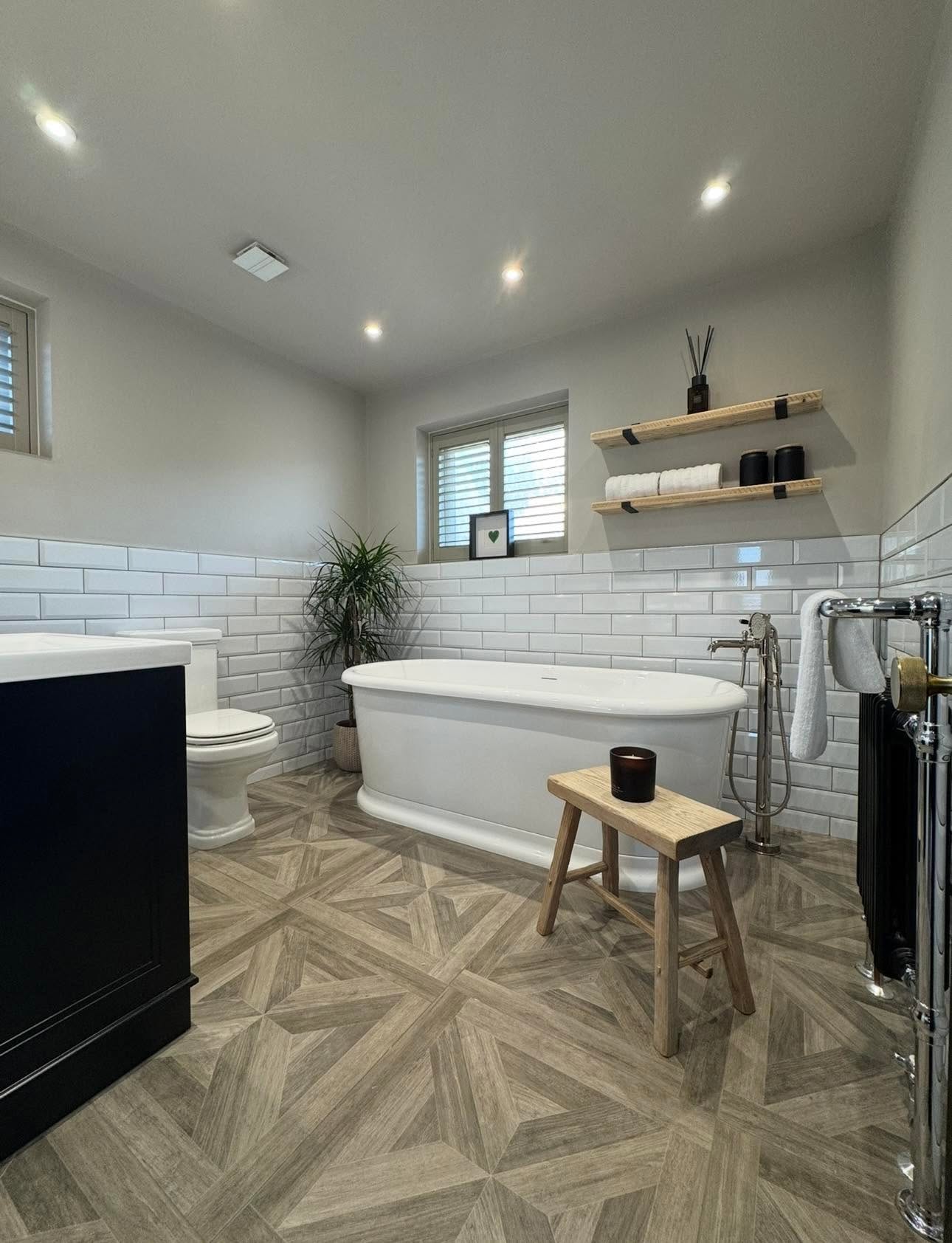 Classic bathroom with freestanding roll top bath, white bevelled metro tiling and patterned wood effect floor