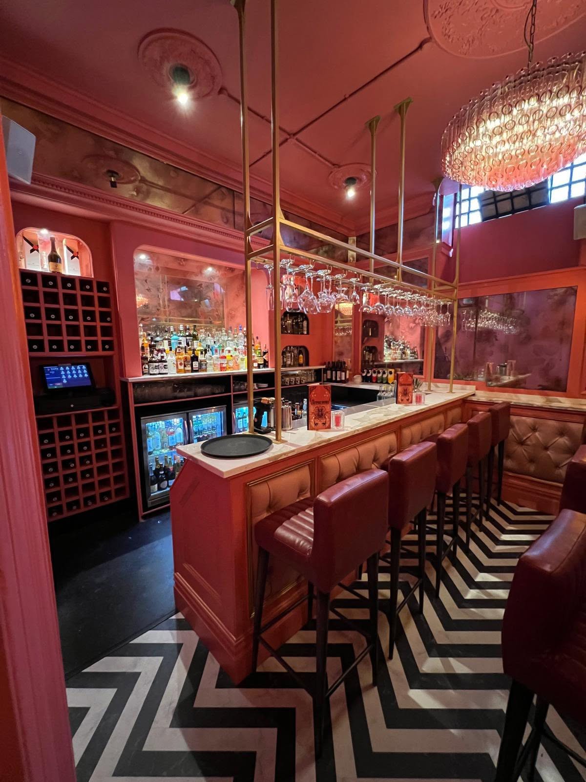 Main bar with brass glass-hanging frame, marble top, wine cube storage and buttoned leather banquettes