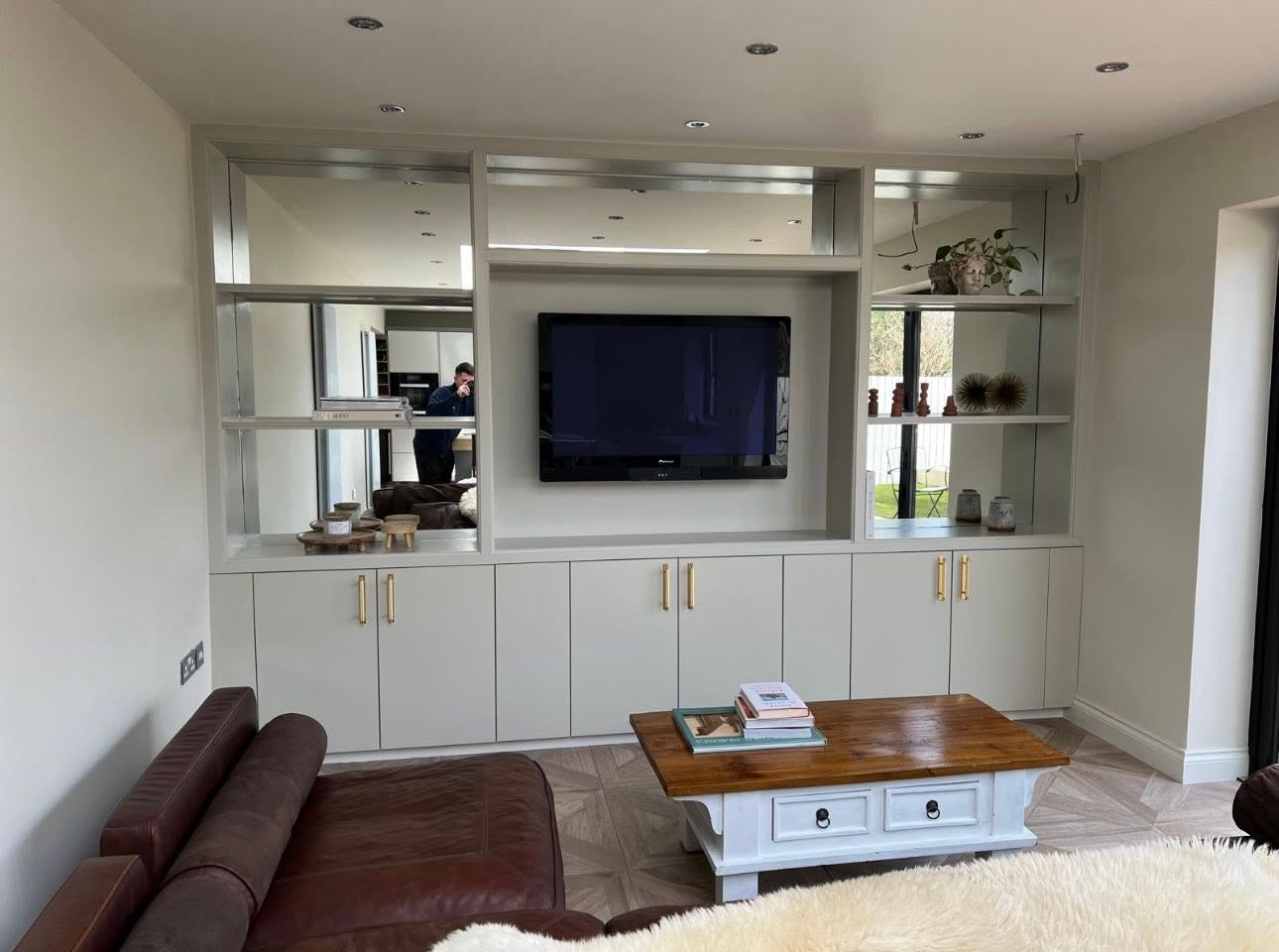 Reverse angle showing black-framed atrium skylight, basket-weave wood floor and built in media unit with mirrored shelving