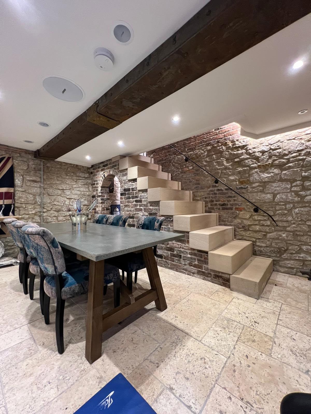 Cantilevered stone staircase with floating sandstone treads set into exposed brick and stone wall