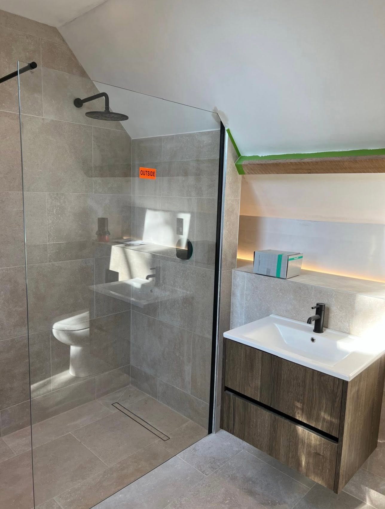 Loft ensuite walk in shower with linear drain, wall hung oak vanity and lit recessed niche