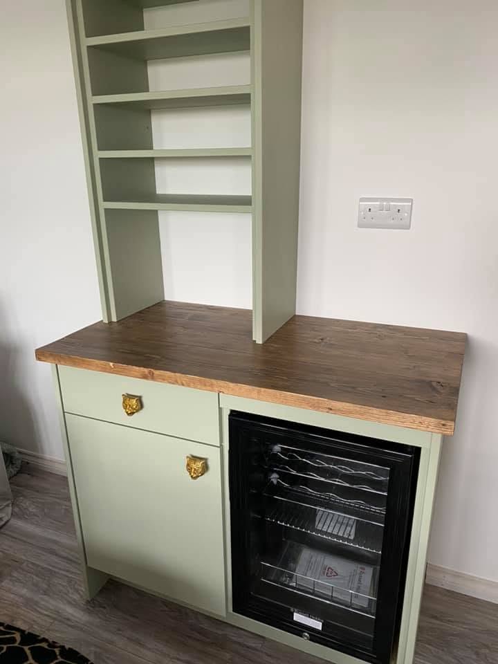 Bespoke sage green drinks cabinet with rustic timber worktop, brass lion head handles, open shelving tower and integrated wine cooler