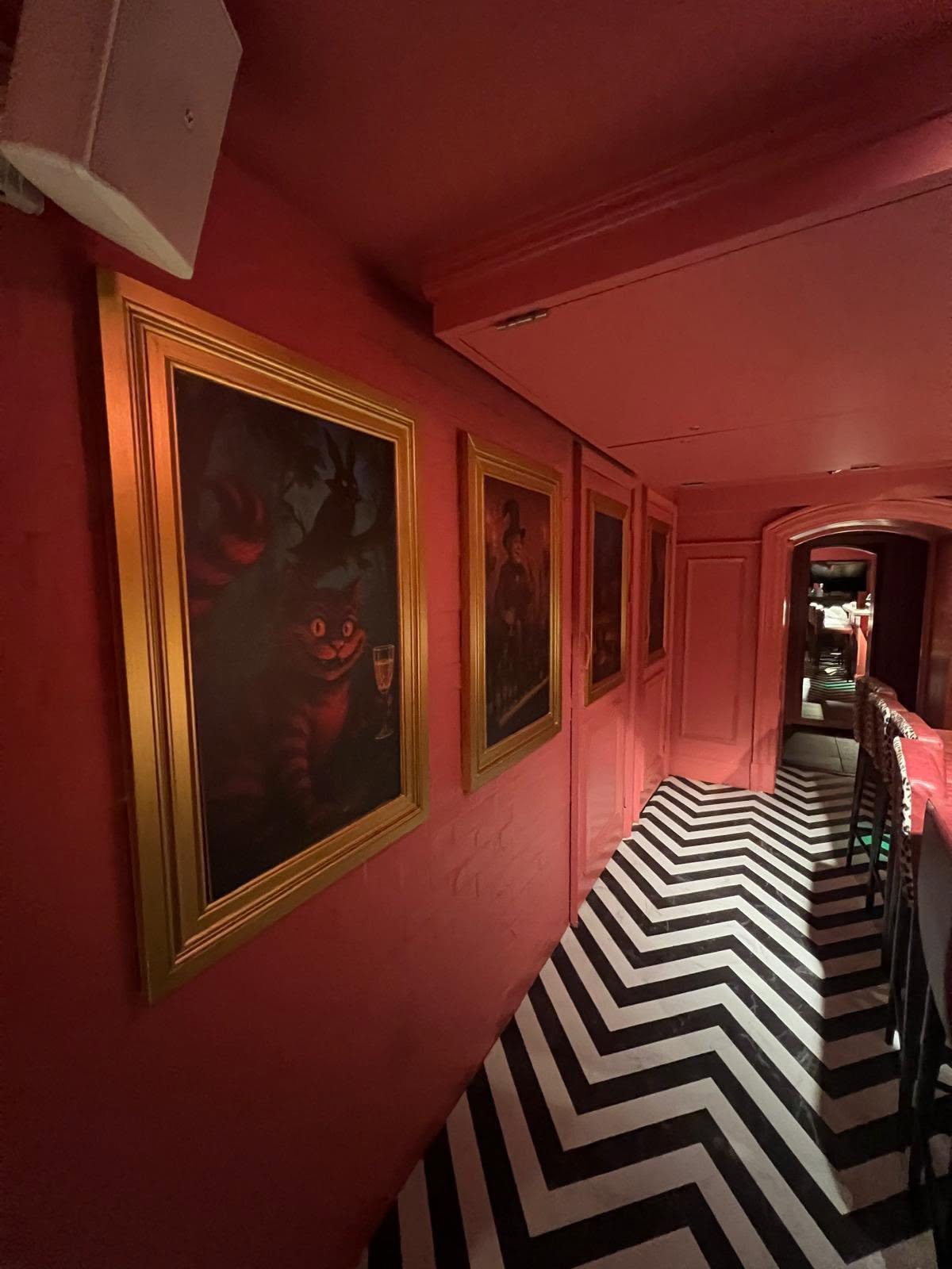 Red corridor with gilt-framed artwork, panelled joinery and chevron marble floor
