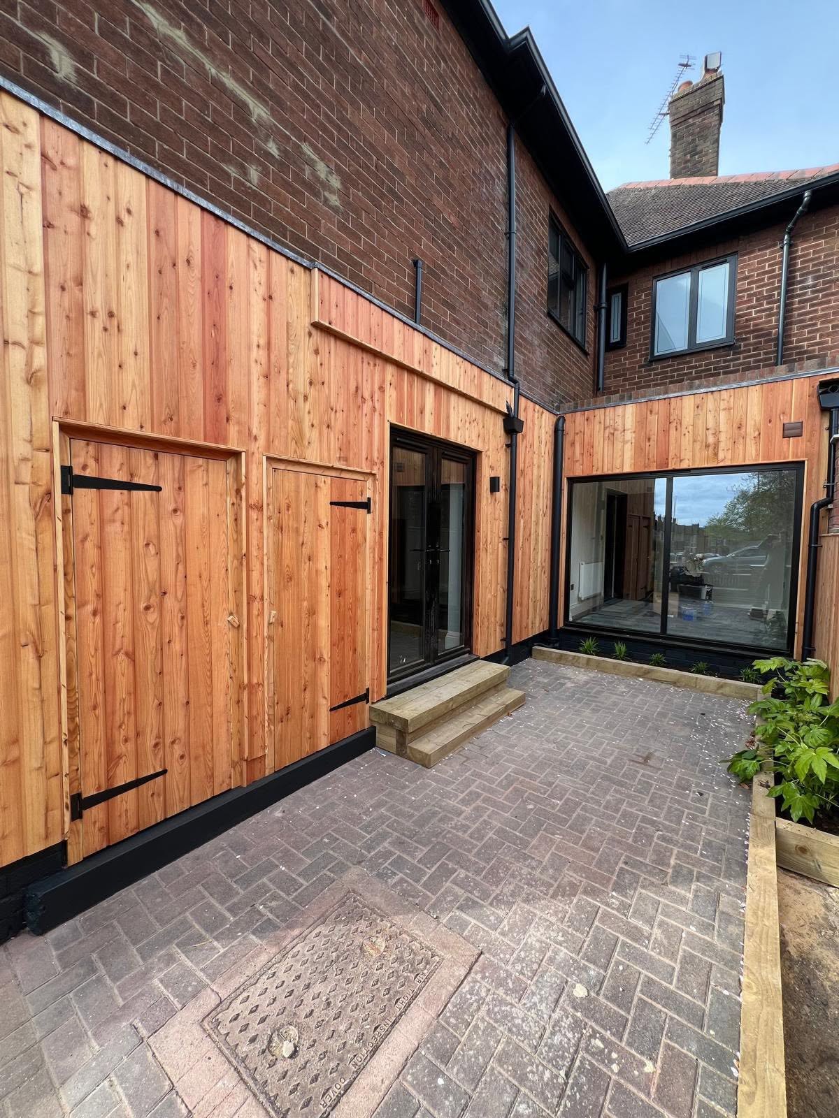 Courtyard with vertical cedar cladding and black double doors