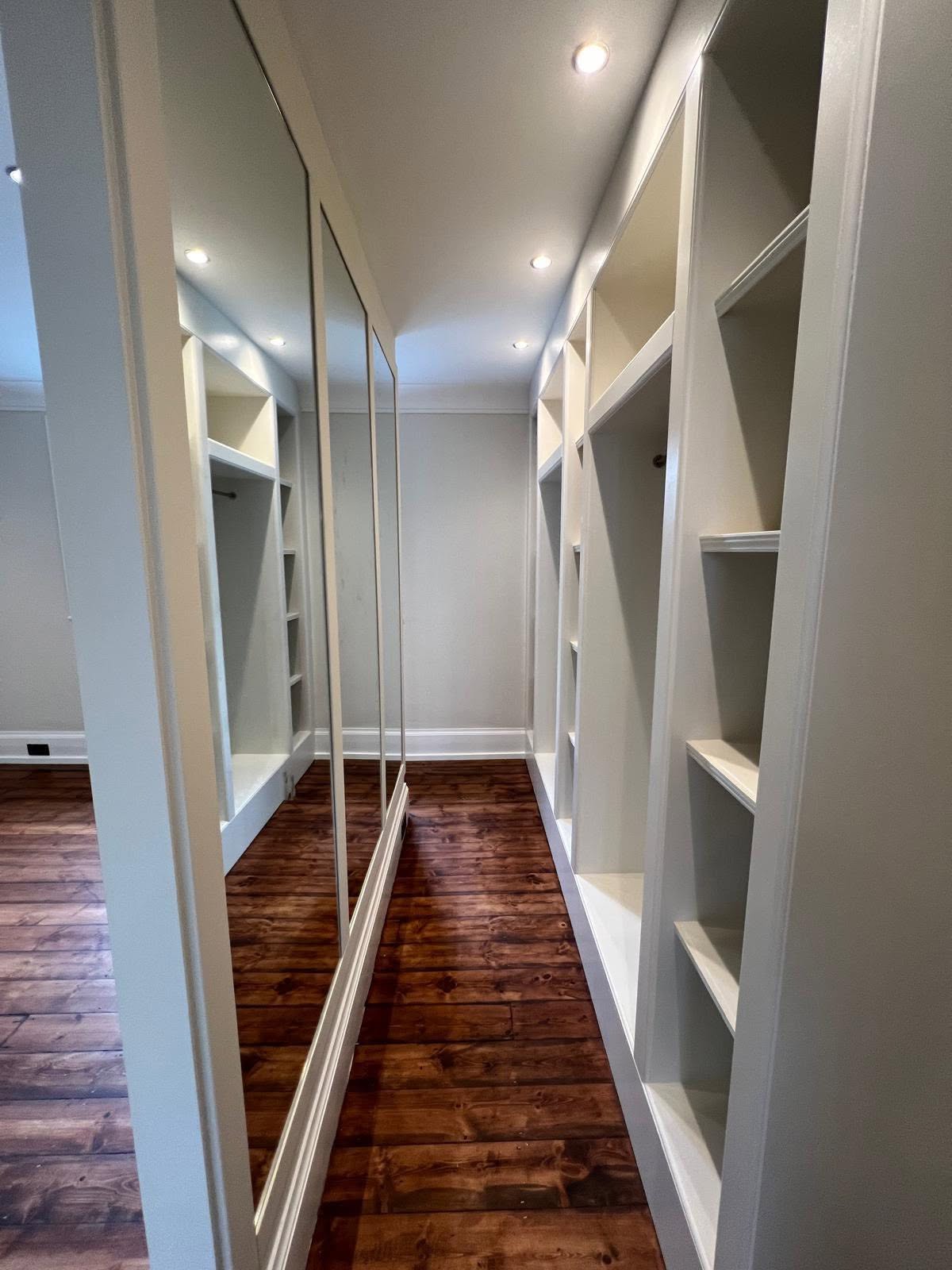 Dressing area with tall mirrors and white recessed shelving