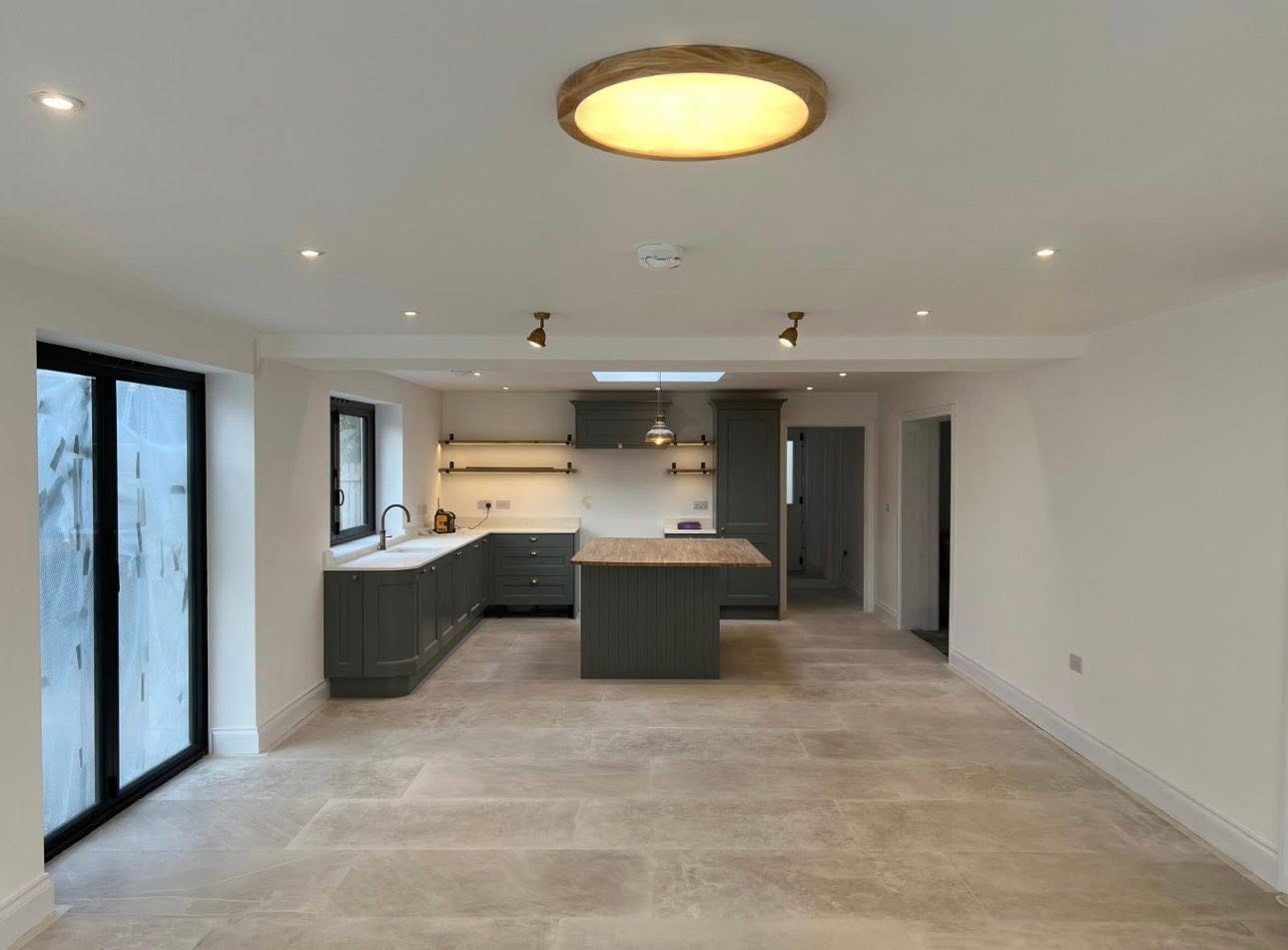 Open plan kitchen extension with black aluminium sliding doors and steel beam