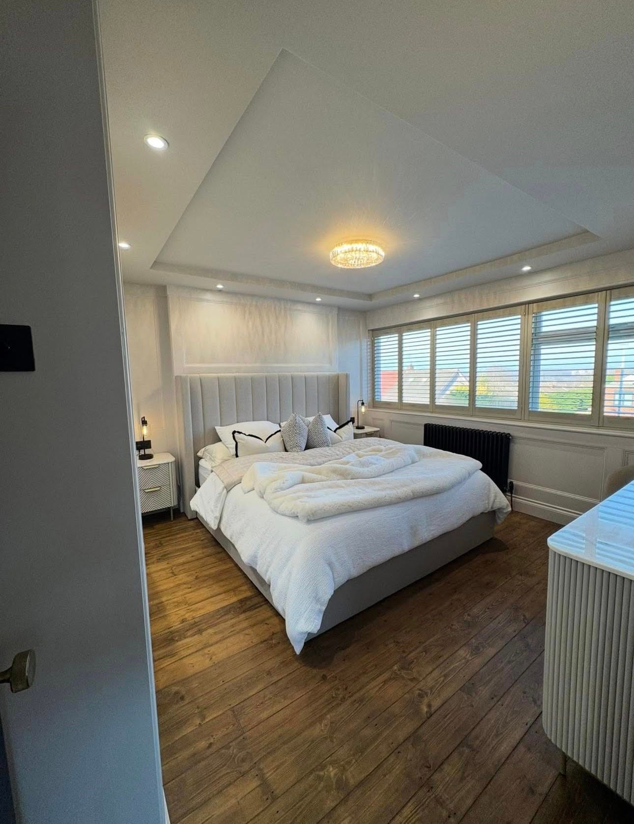 Master bedroom with upholstered headboard and dark timber flooring