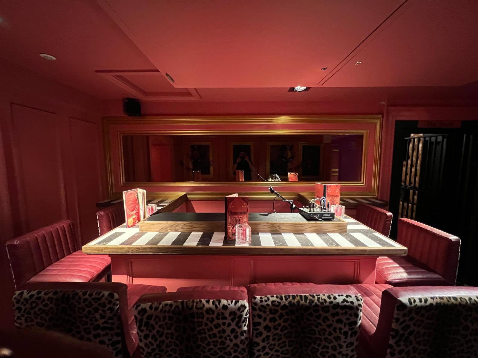 Private booth room with oak-topped island table, inlaid marble stripes and red banquette seating