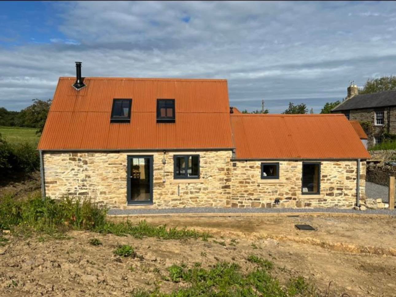 Completed rear elevation with dormer style windows in the metal roof and full height glazed door