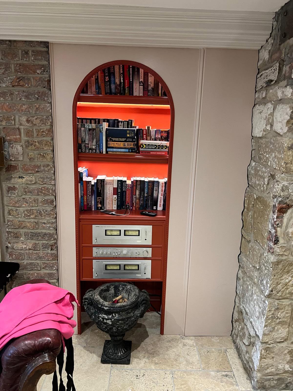 Bespoke joinery detail with red-lacquered arched bookcase, concealed LED shelf lighting and hi-fi bay