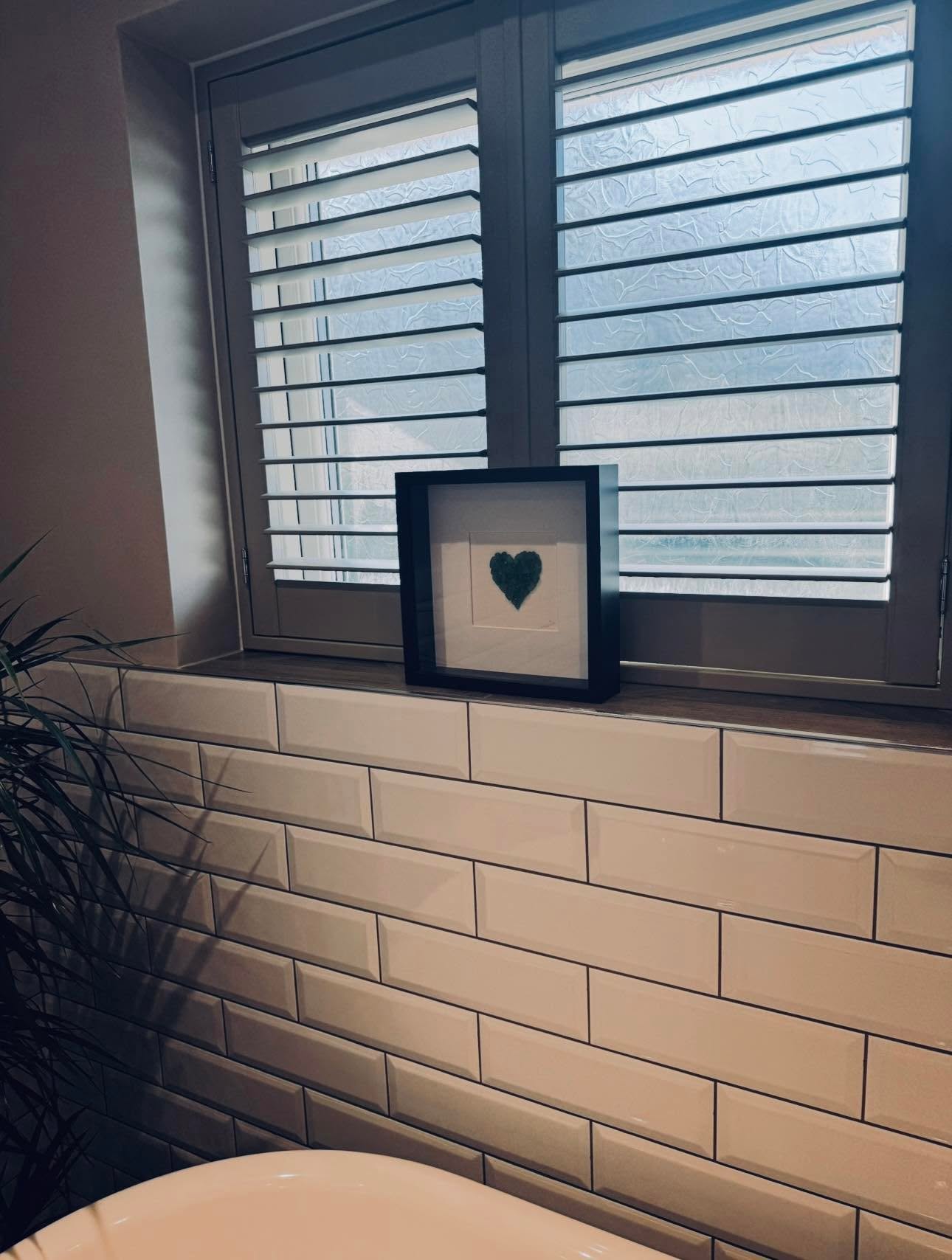 Plantation shutters over the bath with timber sill and metro tiling with dark grout