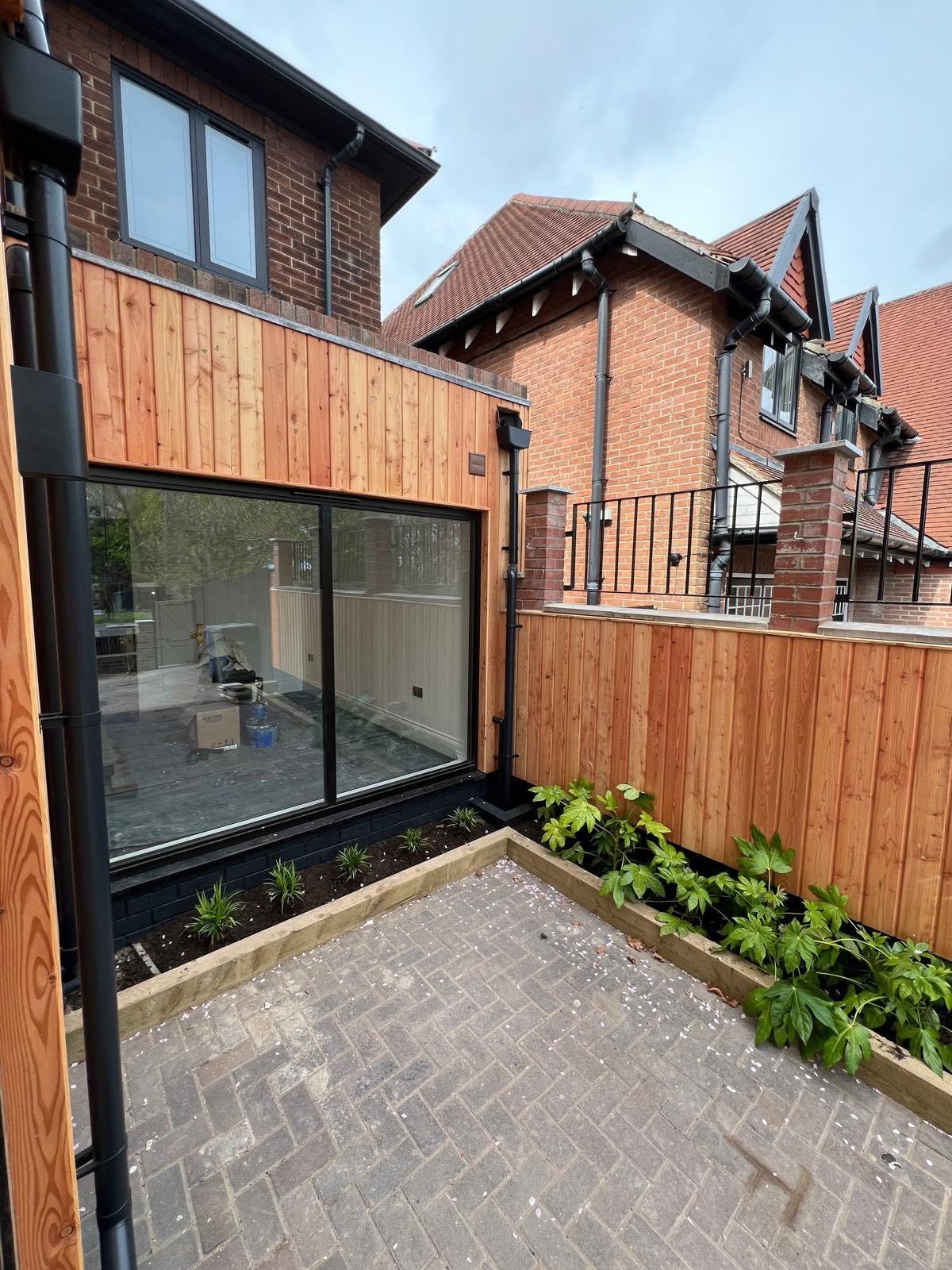 Exterior patio with grey herringbone pavers and vertical wood cladding