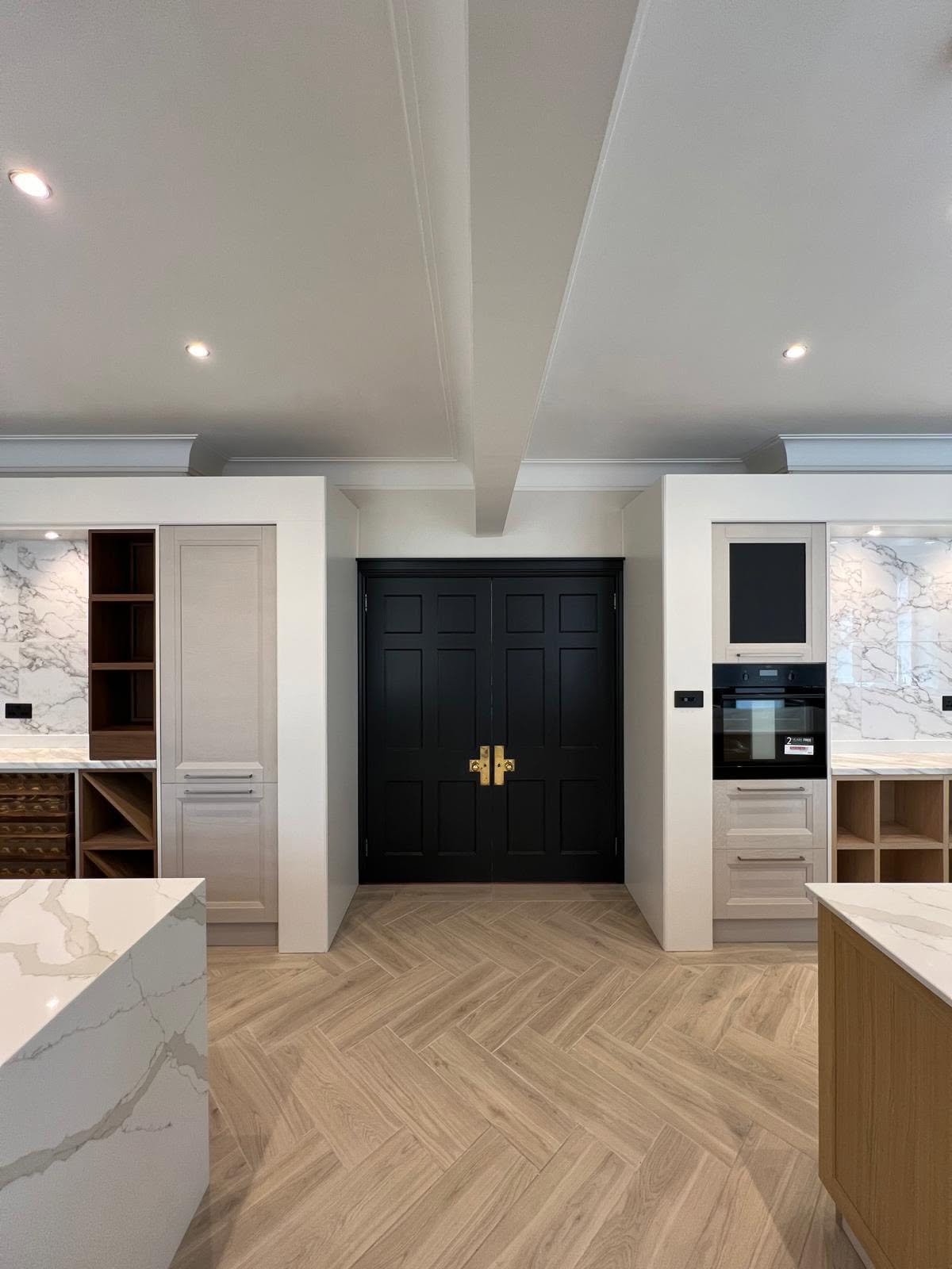 Black framed double doors flanked by fitted white kitchen cabinetry
